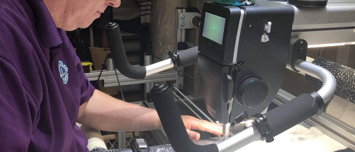 Close-up of the longarm machine head stitching a custom quilt design